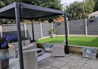 Grey composite fencing around a garden patio with pergola
