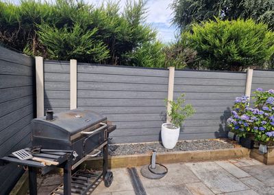 Grey composite fencing around a garden patio with pergola
