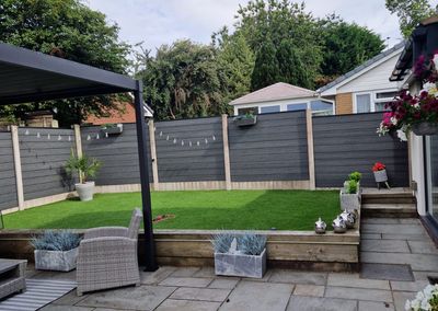 Grey composite fencing around a garden patio with pergola