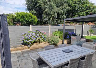 Grey composite fencing around a garden patio with pergola