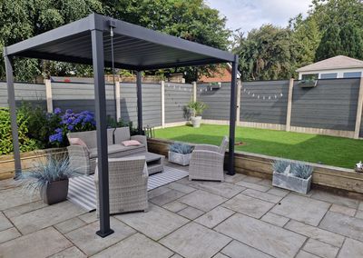 Grey composite fencing around a garden patio with pergola
