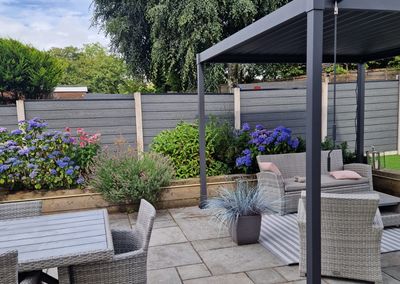 Grey composite fencing around a garden patio with pergola