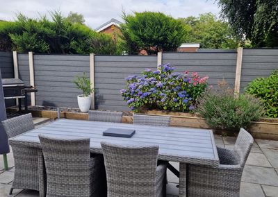 Grey composite fencing around a garden patio with pergola