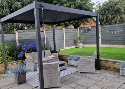 Grey composite fencing around a garden patio with pergola