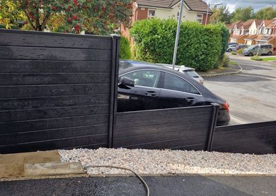 Black composite fencing beside a driveway