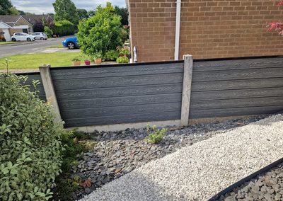 Grey composite fencing above a gravel border