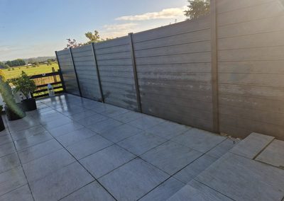 Grey composite fencing around a tiled patio