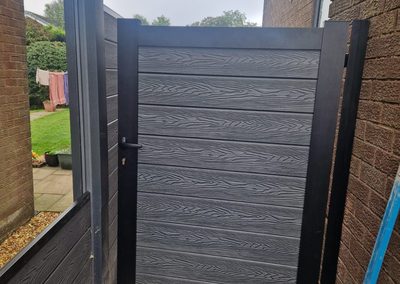 Grey composite side gate between house and fence