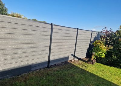 Light grey composite fence along a garden border
