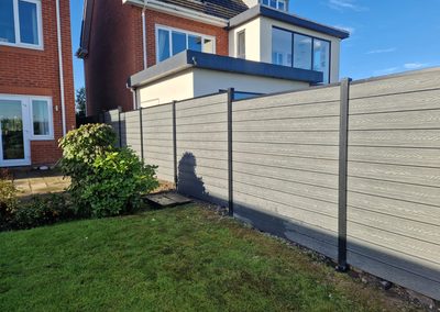Light grey composite fence panels along a lawn